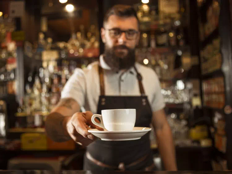 Barista trzymający filiżankę z kawą